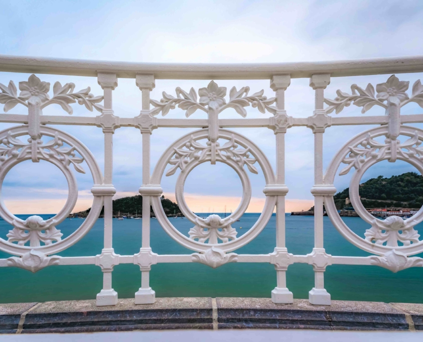 La Concha bay and beach viewed through an ornate metal balustrade of the promenade Paseo de la Concha in San Sebastian Donostia, Basque Country, Spain